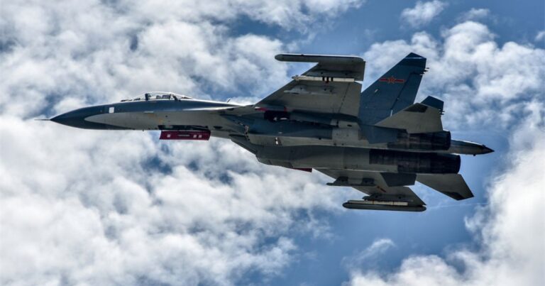 U.S. flag with fighter jet silhouette against sky