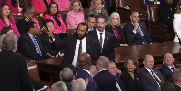 Rep. Al Green holding a banner during the State of the Union before being escorted out.