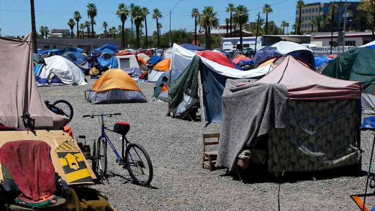 Los Angeles homeless encampment with city skyline in the background