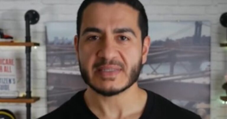Abdul El-Sayed wearing a pink poncho during a Detroit storm damage visit